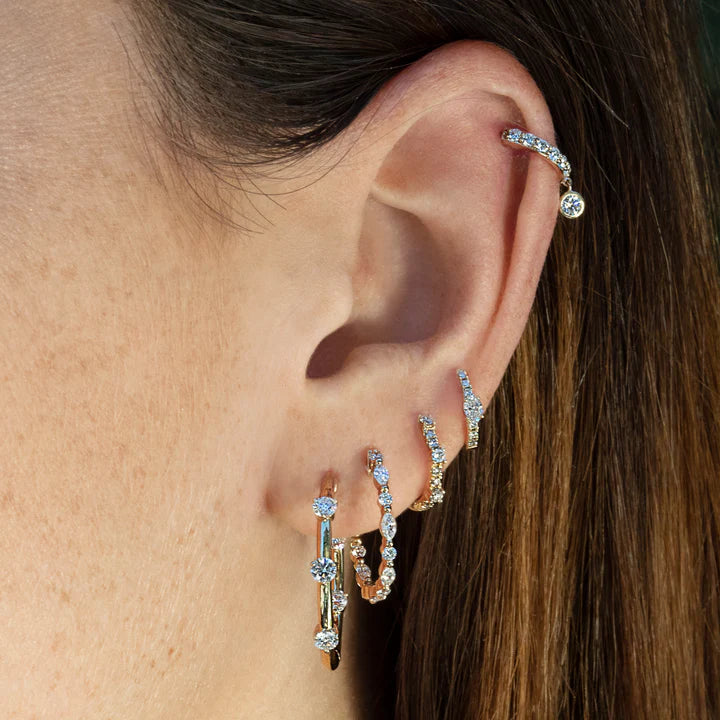 Close-up of an ear wearing multiple diamond hoop earrings.