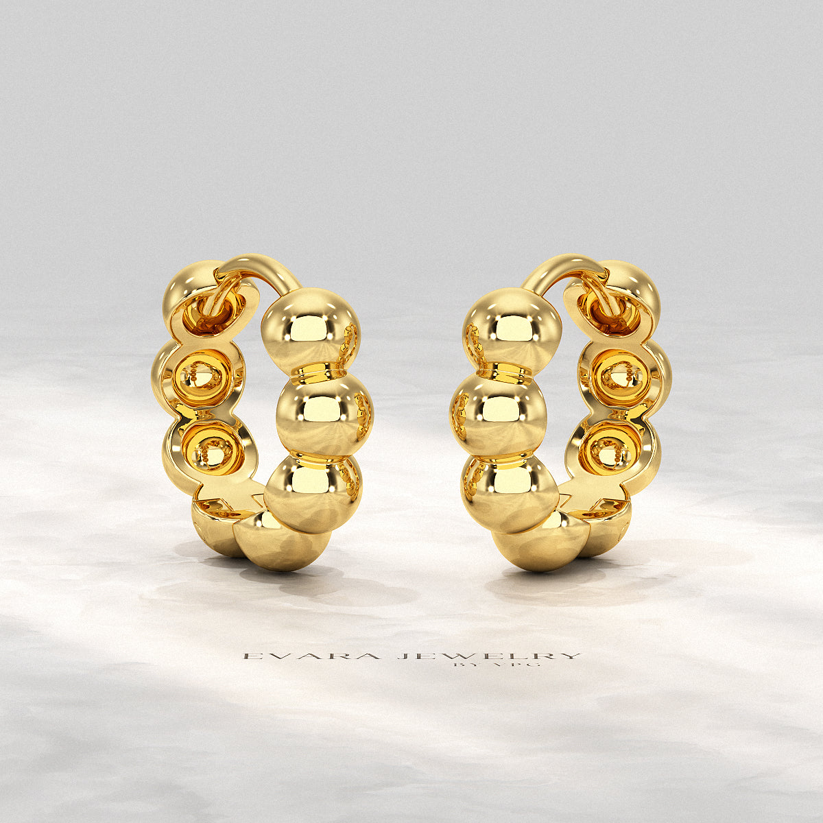 Hand holding a pair of bold bubble bead hoop earrings for size reference.