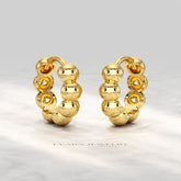 Hand holding a pair of bold bubble bead hoop earrings for size reference.